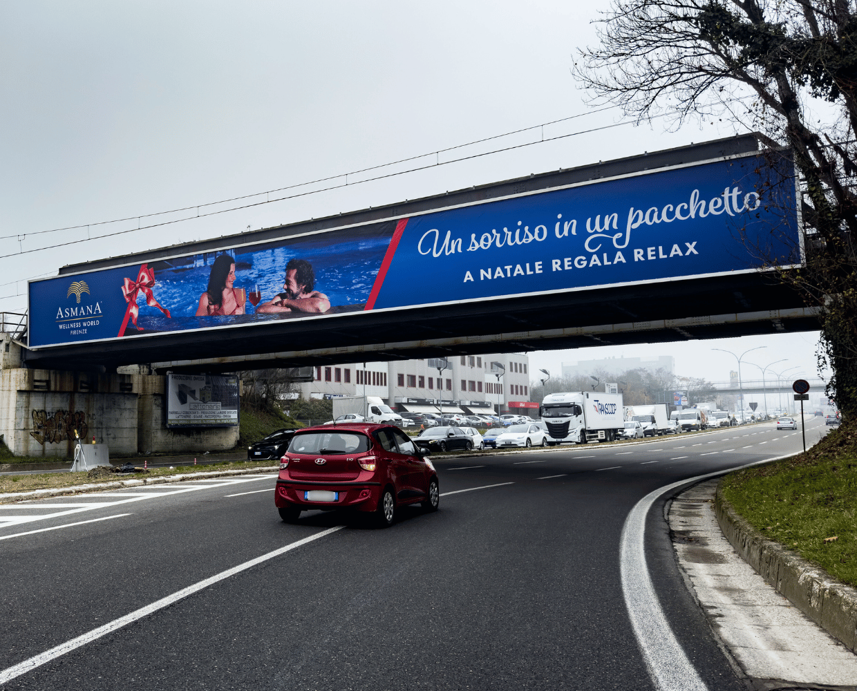 Auto rossa passa sotto ad un bridge banner per affissioni a Bologna